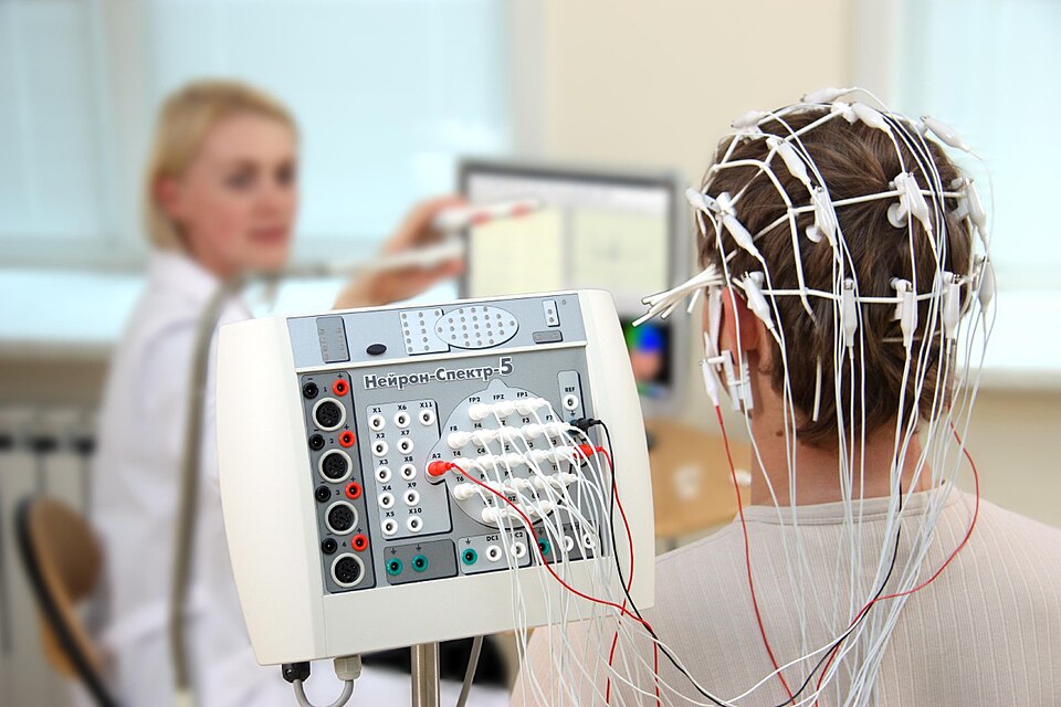 Technologist preparing an EEG recording with a capped patient